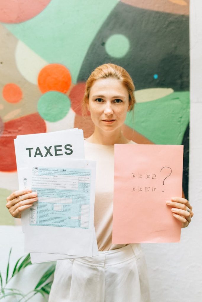 woman-holding-pink-and-white-papers-8927644 A professional woman holding tax documents and a Need Help? sign, offering tax assistance.